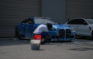 a detailer washing a blue bmw